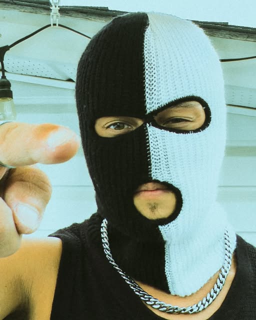 Person wearing a split black-and-white balaclava and chain.